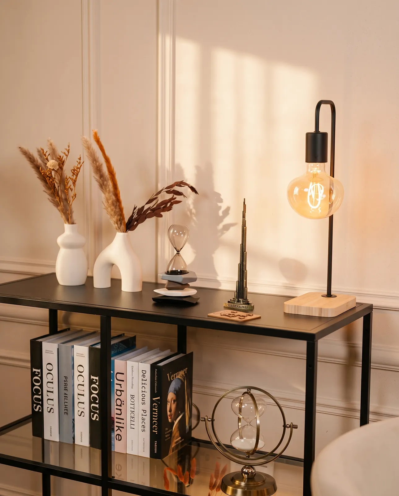 Studio shelf with art books, dried pampas and a brass Burj Khalifa model — Podflix Studio, Business Bay Dubai