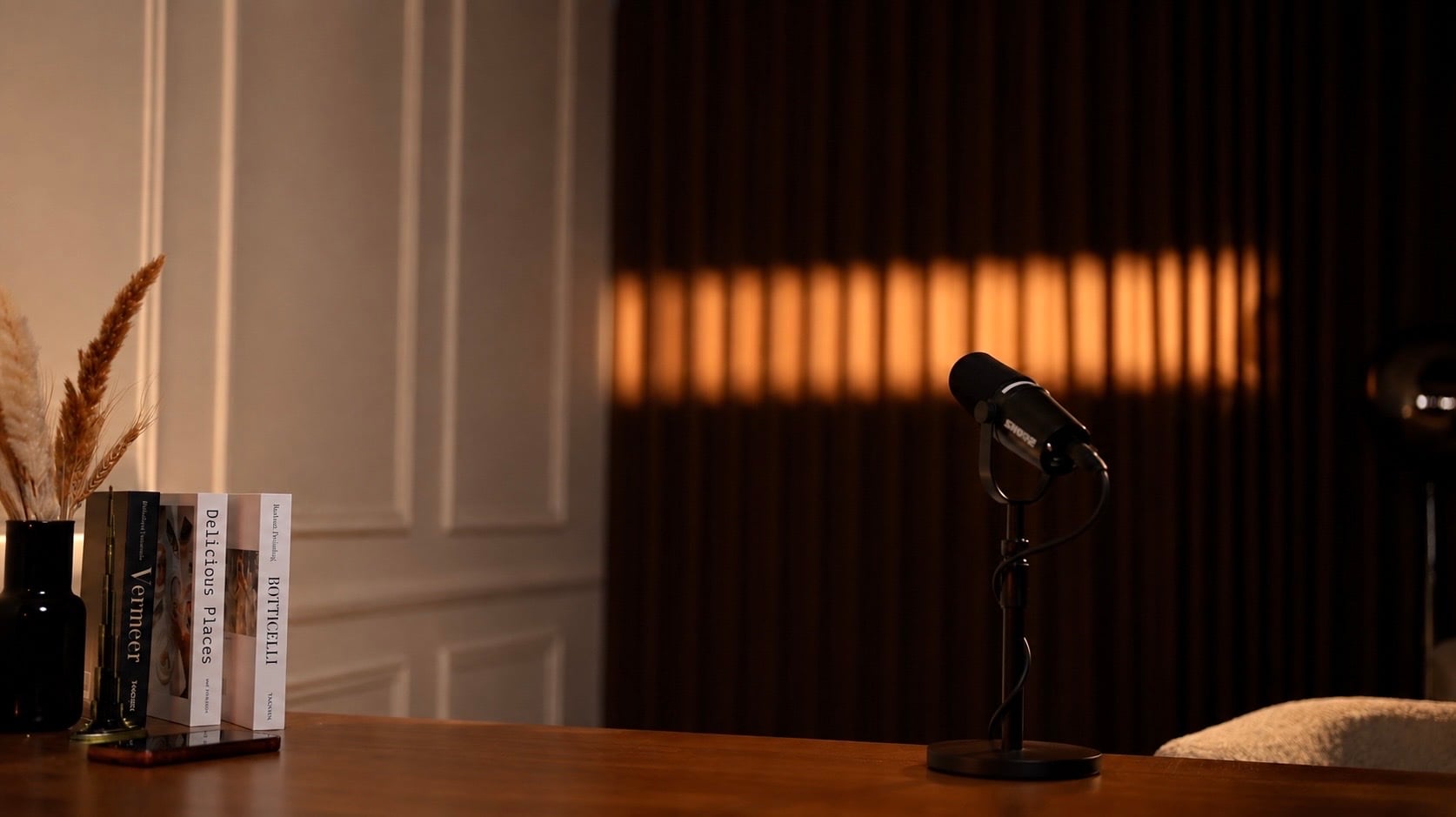 Minimal solo podcast desk set under warm slatted light — Podflix Studio Dubai
