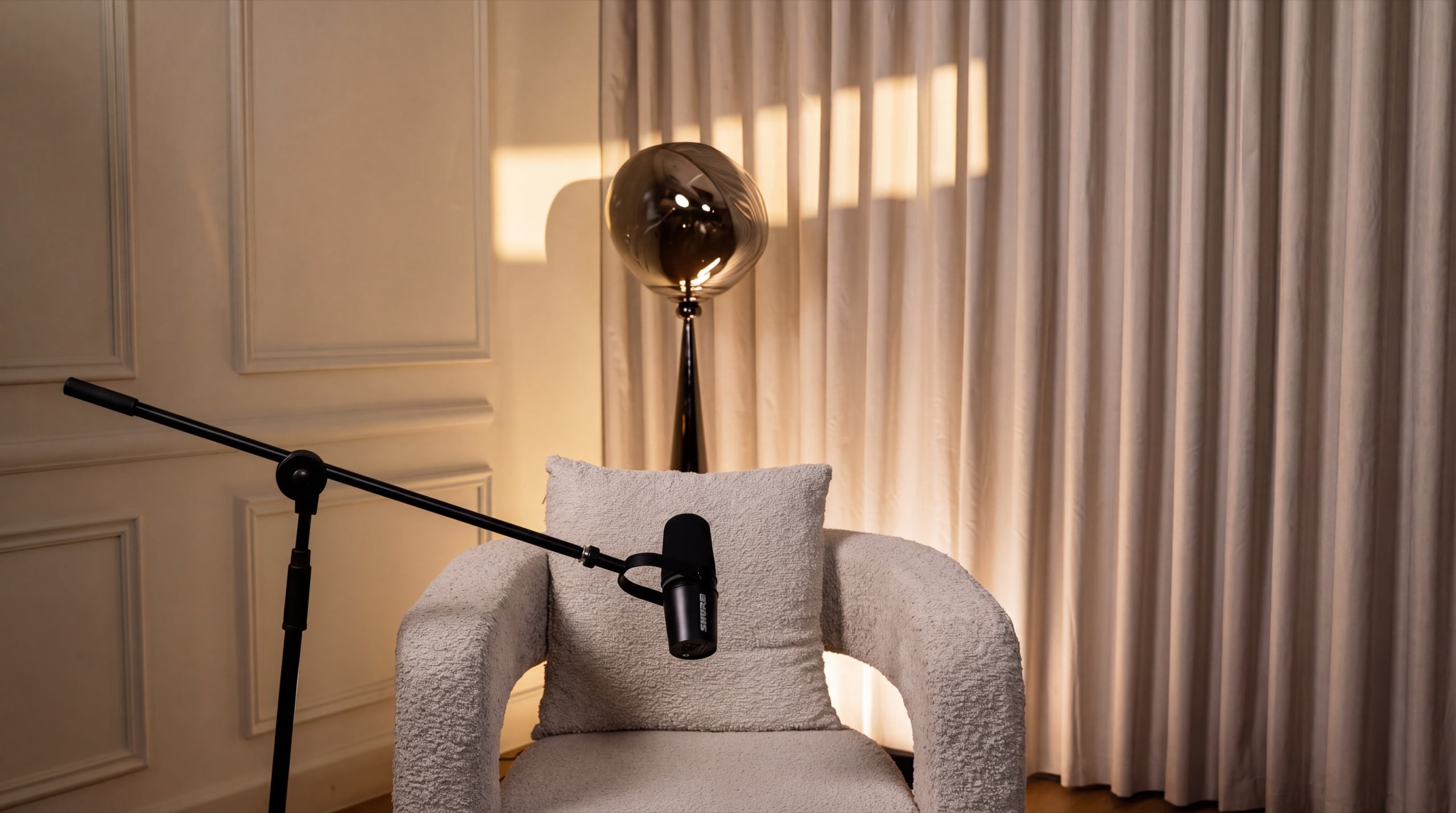 Bright editorial solo podcast set beneath a gold orb lamp — Podflix Studio Dubai